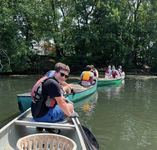 a group of teens from the Teen JUST-US program in three canoes - the closest teen is looking back at the camera and smiling