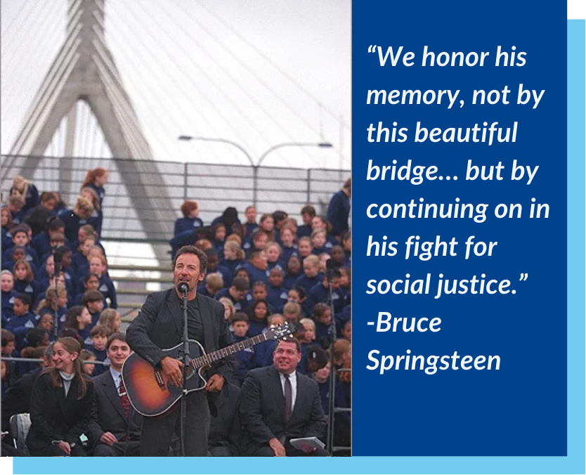 To the left, a picture of Bruce Springsteen with a guitar, wearing all black, standing in front of a microphone with a crowd of people behind him consisting of some people in formal attire and mostly kids in blue shirts. To the right, light, italicized text on a blue background that reads 'We honor his memory, not by this beautiful bridge... but by continuing on in his fight for social justice. -Bruce Springsteen'